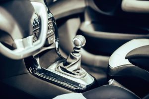 Close-up of a car's manual gear shift surrounded by a sleek black and silver interior. Soft focus creates a modern, sophisticated feel.