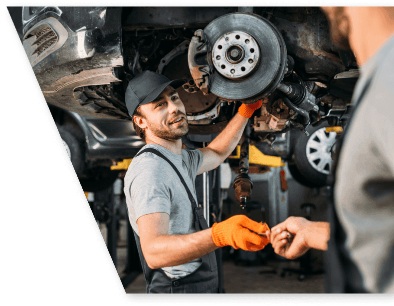 mechanic handing a tool to another mechanic repairing a car