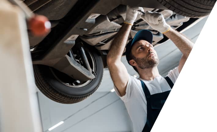 car mechanic working underneath a car on a lift